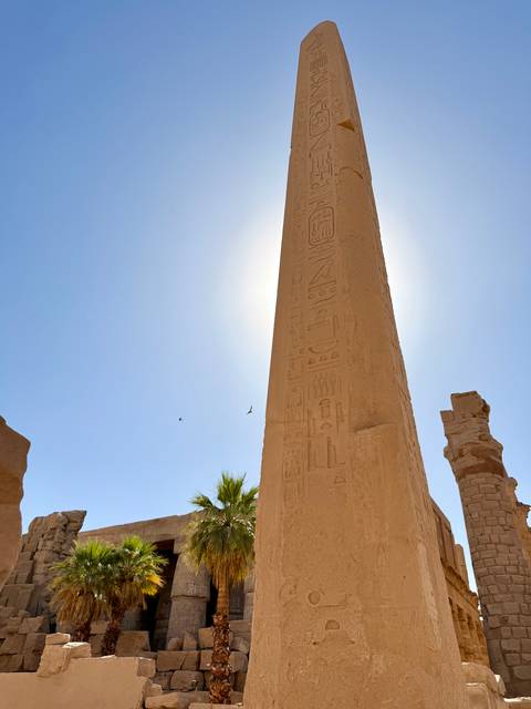       Ancient obelisk with hieroglyphs standing tall against the bright sunlit sky
  