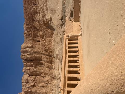      Temple of Hatshepsut backed by sheer desert cliffs under a deep blue sky
  