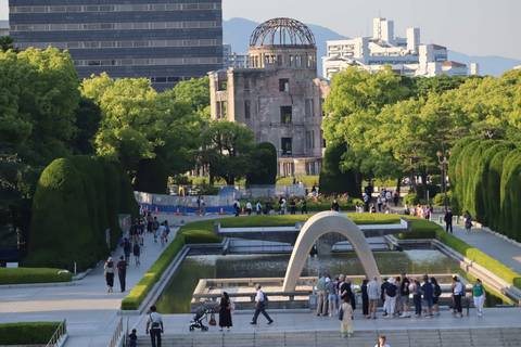       View across Hiroshima Peace Memorial Park with the A-Bomb Dome framed by greenery
  