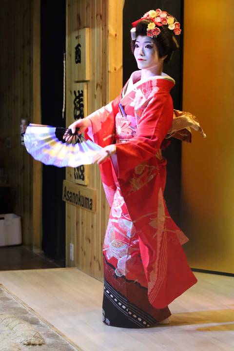       Traditional performer in red kimono gracefully dancing with a folding fan
  