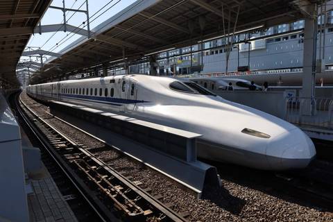       Sleek white Shinkansen bullet train waiting at a covered station platform
  
