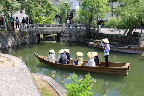       Traditional flat-bottomed boat with straw-hat passengers gliding along a green canal
  
