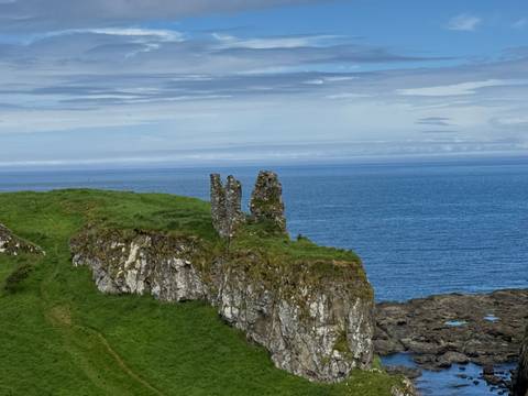       Ruined stone tower perched on grassy sea cliff overlooking the Atlantic
  
