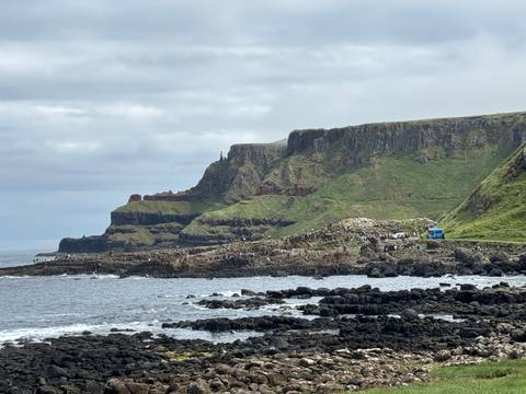       Wide coastal scene of Giant's Causeway with visitors walking among basalt rocks
  