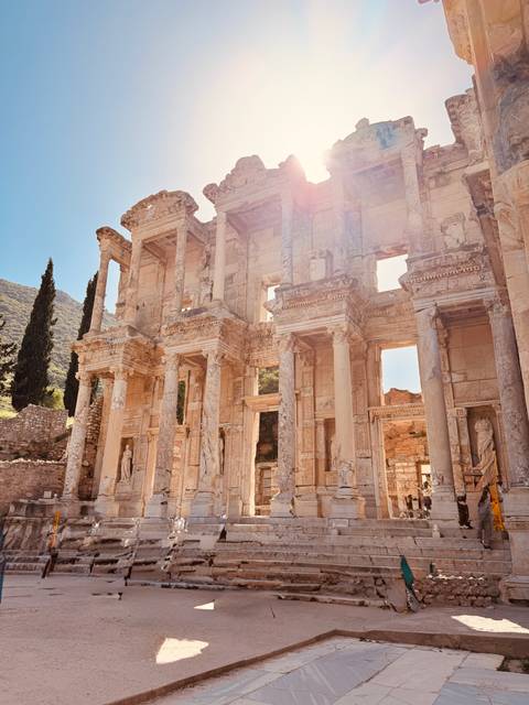       Sunlit façade of the ancient Library of Celsus with dramatic columns and statues.
  