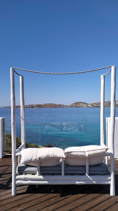       Framed seascape view of tranquil bay and hills from resort cabana posts.
  