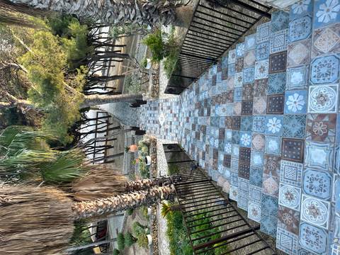       Long, patterned staircase decorated with colourful ceramic tiles leading through a shaded garden.
  