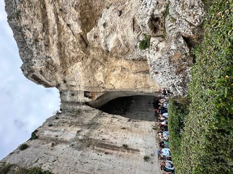       Crowds gather at the entrance of the massive limestone cave known as the Ear of Dionysius in Syracuse.
  