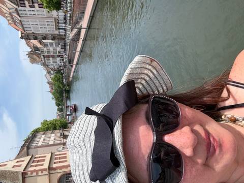       Partial selfie of a woman in sunglasses by the canal and historic houses of Strasbourg.
  