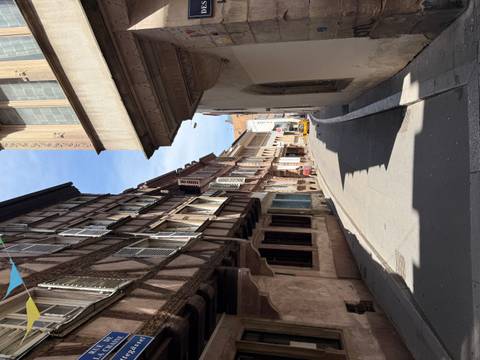       Narrow cobblestone street flanked by half-timbered medieval houses with shuttered windows under a blue sky.
  