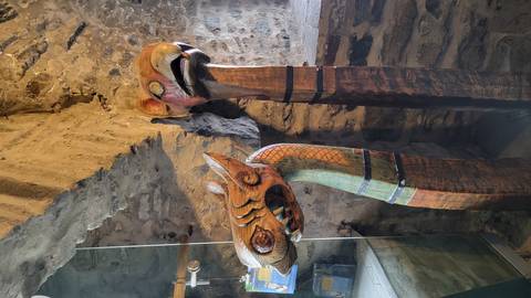       Two carved wooden Viking-style animal heads displayed inside a stone chamber.
  