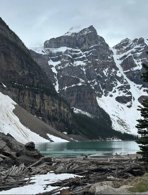       Steep rocky mountainside with patches of snow and dark cliffs in early summer.
  