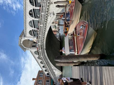       Motorboats docked near the iconic Rialto Bridge spanning the Grand Canal.
  