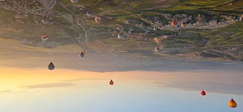       Dozens of hot-air balloons drift over Cappadocia’s valleys at sunrise.
  