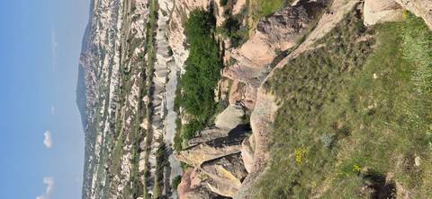       Expansive view of green valleys and rock pinnacles in Cappadocia.
  