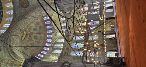       Ornate interior of the Blue Mosque bathed in natural and chandelier light.
  