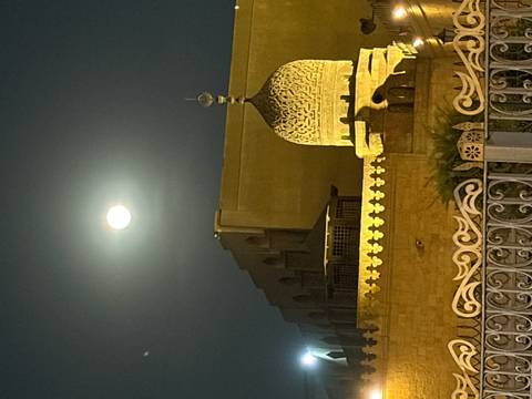       A full moon glows above an ornate mosque dome against the night sky in Cairo.
  