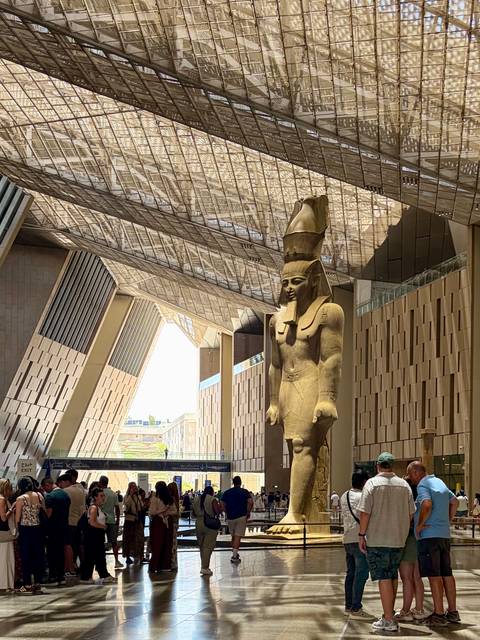       Massive pharaoh statue stands inside the modern atrium of the Grand Egyptian Museum.
  
