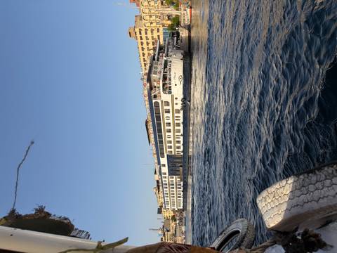       A large white Nile cruise ship sails along the river with city buildings in the background.
  