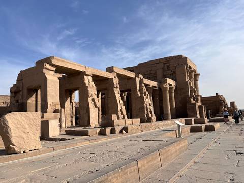       Wide angle view of sandstone temple ruins with visitors walking along the ancient stone path.
  