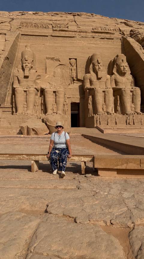       Traveller sitting on a bench before the massive rock-carved façade of Abu Simbel temple.
  
