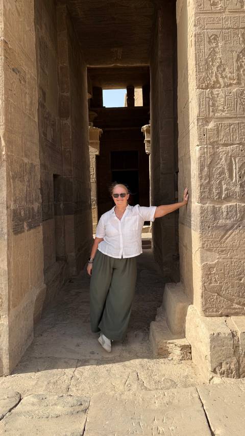       Woman leaning casually in the shaded doorway of an ancient stone temple.
  