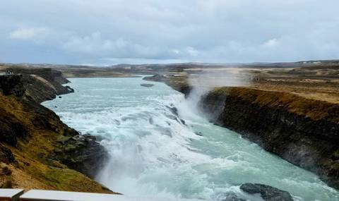       Mighty Gullfoss waterfall thundering through a rugged canyon, spray rising dramatically into the air.
  