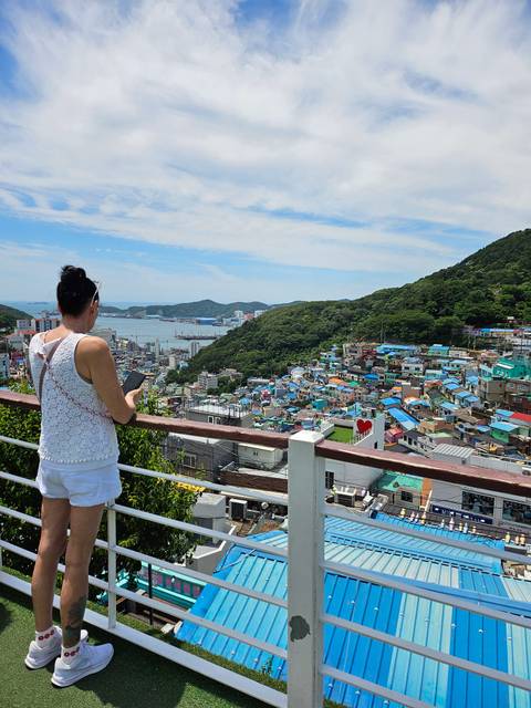       A traveler views the colorful hillside homes of Gamcheon Culture Village overlooking Busan’s harbor.
  