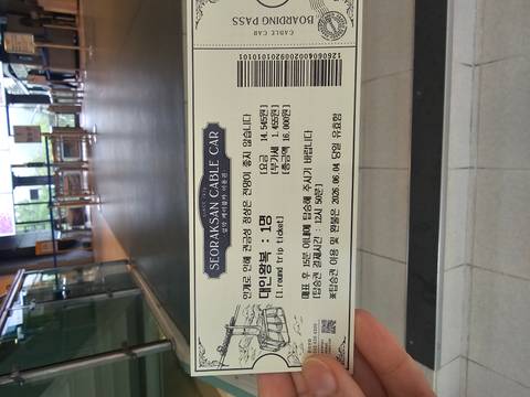       Close-up of a Seoraksan cable car ticket held in an indoor station area.
  