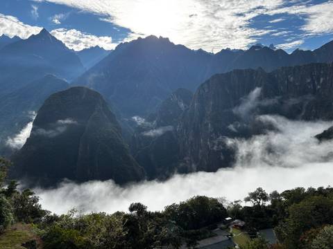       Dramatic mist filling a deep gorge with steep green peaks and a backlit sky above the Andes
  