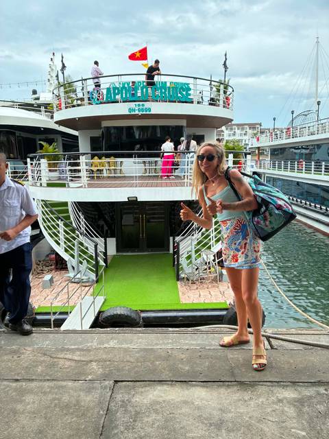       Smiling traveller giving thumbs-up while boarding a cruise boat at a marina.
  