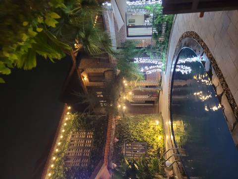       Nighttime courtyard of a boutique hotel with pool, ivy-covered walls and warm string lights.
  
