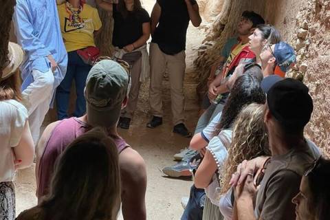       Tour group listens inside a narrow earthen passageway of a Moroccan kasbah.
  