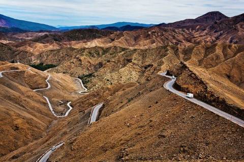       Serpentine mountain road weaves through barren brown ridges of the High Atlas.
  