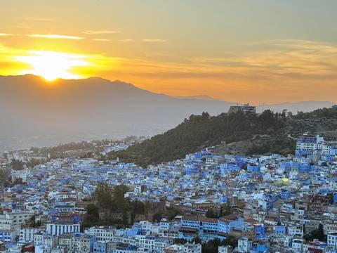       Sunset over the Rif Mountains illuminating the blue-washed town of Chefchaouen sprawling below.
  
