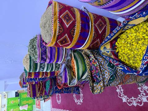       Stacks of colorful woven baskets overflowing with spices and herbs in a Moroccan market.
  