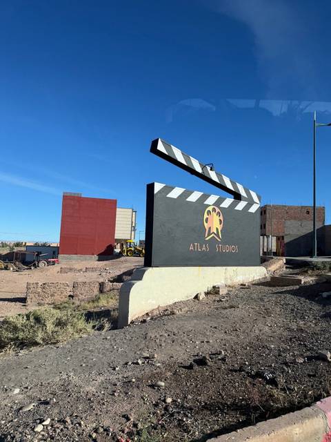       Cinematic clapperboard monument reading Atlas Studios stands in the Moroccan desert.
  
