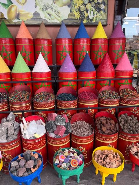       Colorful conical spice tins filled with vibrant crystals on display at a Moroccan market stall
  