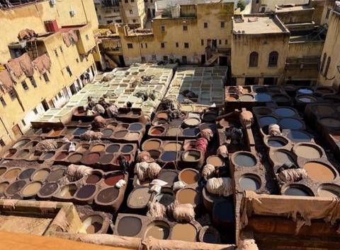       Overhead view of the Chouara leather tannery with workers tending circular dye vats in Fes
  