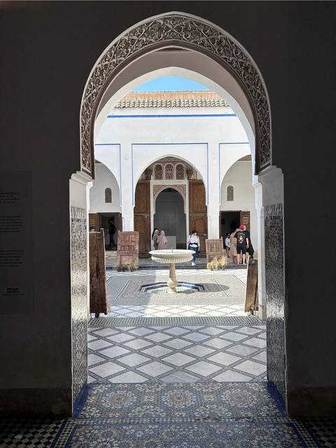       Intricate tiled courtyard with a central fountain and carved wooden doors inside Bahia Palace
  