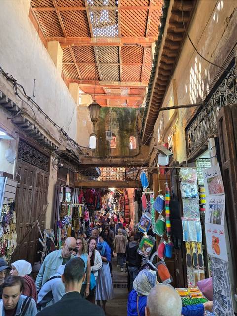       Bustling narrow souk corridor filled with colorful merchandise and shoppers
  