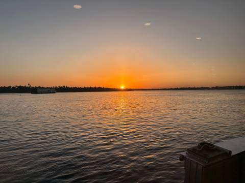       Sun sets over the Nile River casting an orange glow across calm waters.
  