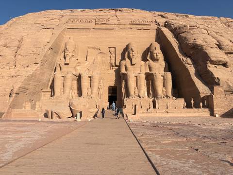       Majestic façade of Abu Simbel Great Temple with four seated statues of Ramses II carved into the sandstone cliff.
  