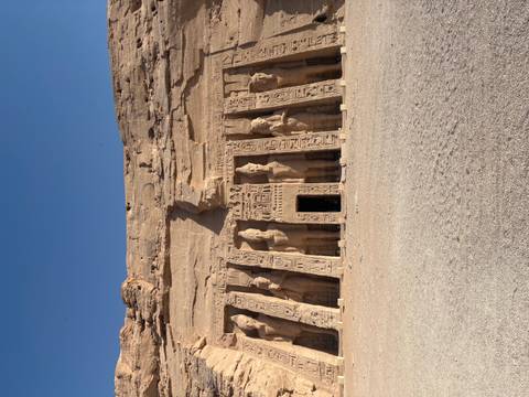       Smaller temple of Abu Simbel dedicated to Nefertari featuring standing statues carved into a rock façade under clear skies.
  