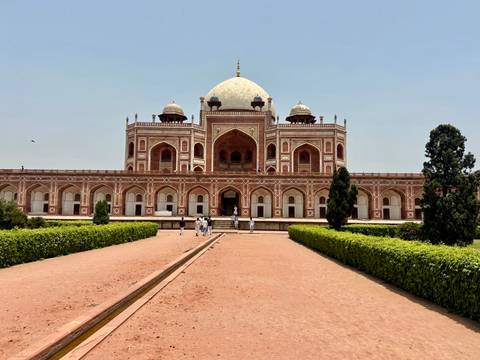       Wide view of Humayun’s Tomb framed by courtyard and blue sky.
  
