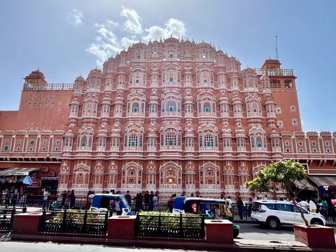       Detailed pink sandstone façade of Hawa Mahal with bustling street activity below.
  