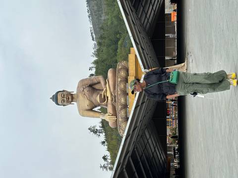       Tourist poses beneath the massive seated Buddha Dordenma statue in Thimphu, Bhutan.
  