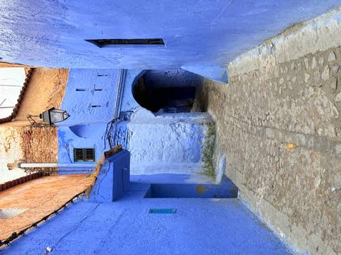       Quiet blue alleyway in Chefchaouen with arched doorway, lantern and cobblestone path
  