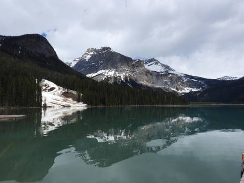       Snow-capped Rocky Mountains reflecting in a calm turquoise lake fringed by conifer forest.
  