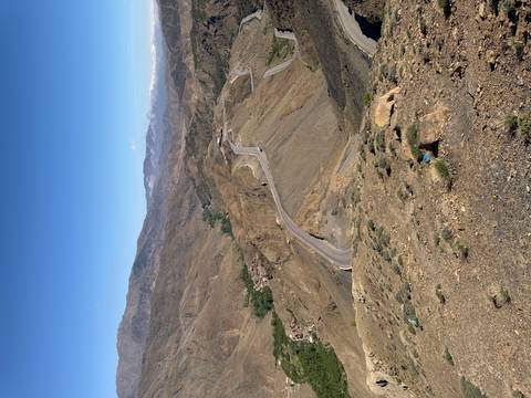       High-altitude serpentine mountain road carving through rugged brown terrain.
  
